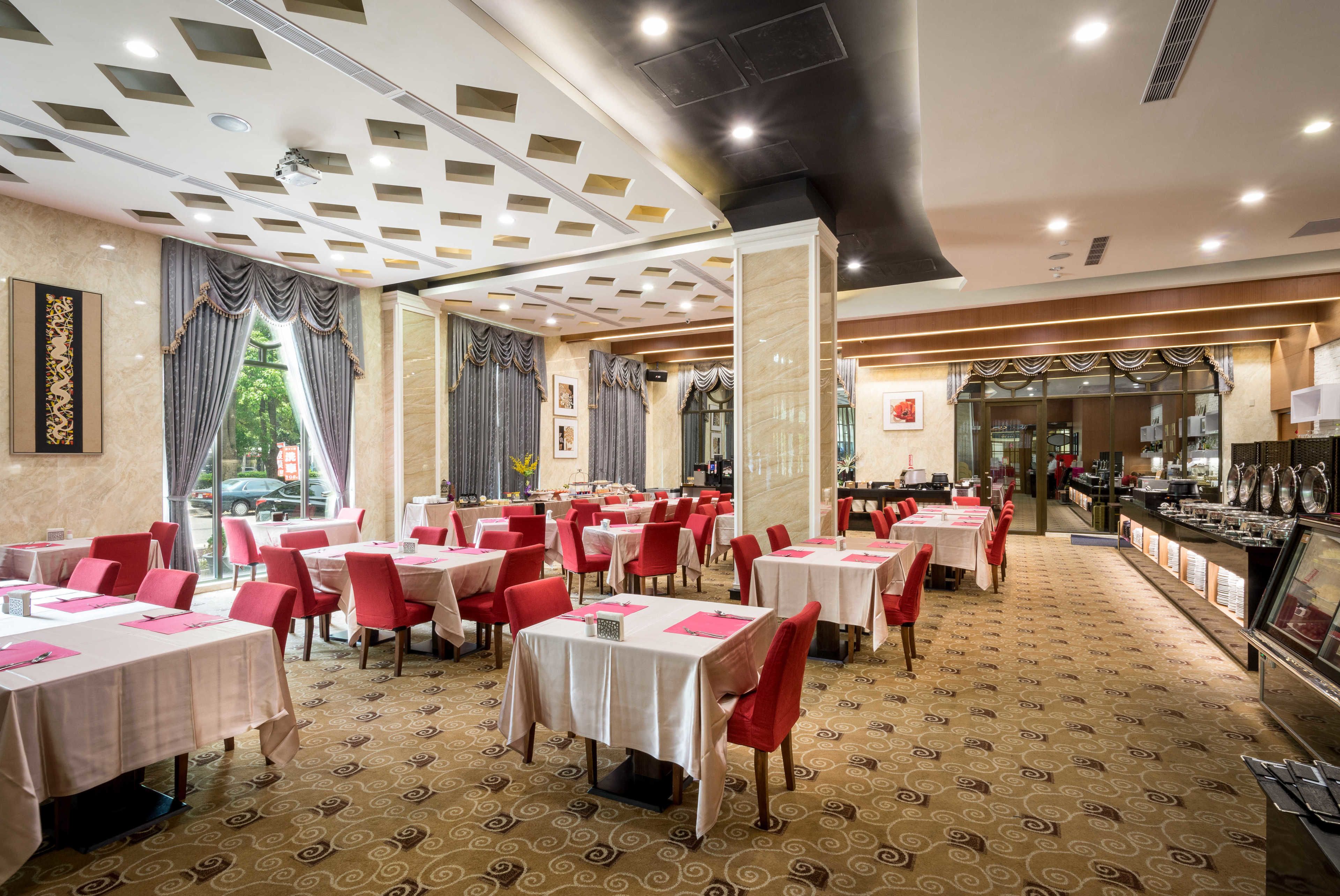 Un restaurante con mesas y sillas, una alfombra estampada e iluminación empotrada en el techo.