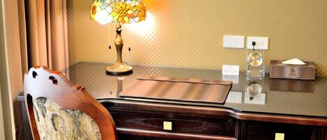 A wooden desk with a stained glass lamp, a chair with a patterned cushion, and a small wooden box on the desk.