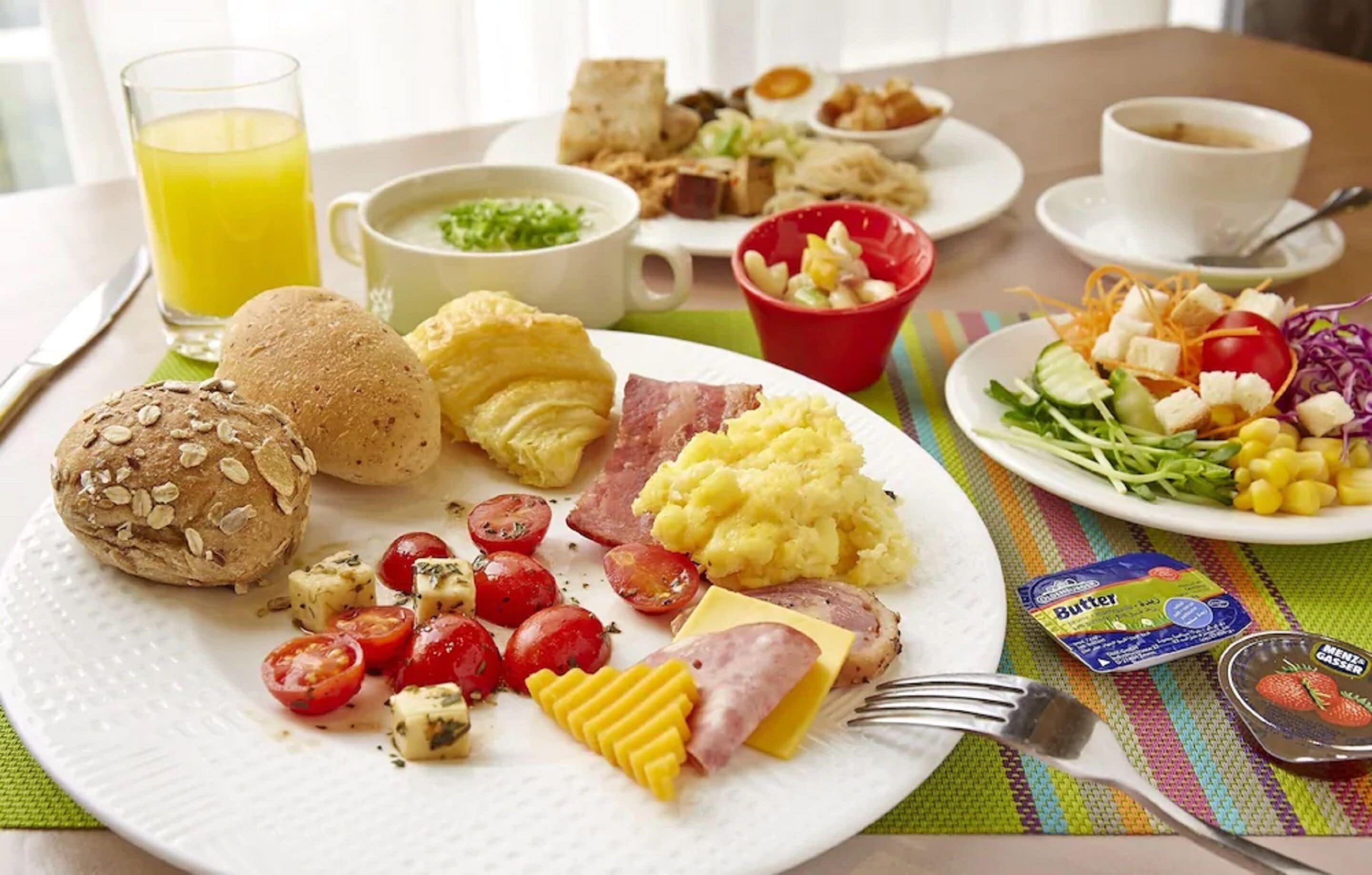 A breakfast table with various foods, including eggs, toast, and a salad.