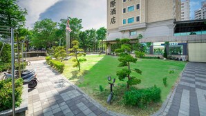 A hotel courtyard with a paved walkway, neatly trimmed grass, and a few trees. - Royal Chiayi Hotel (Chiayi City)