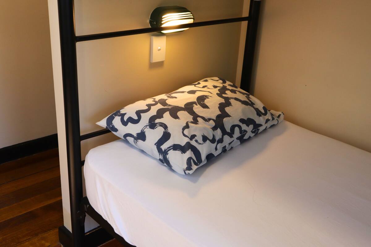 A bunk bed with a patterned pillow and a wall-mounted light fixture.