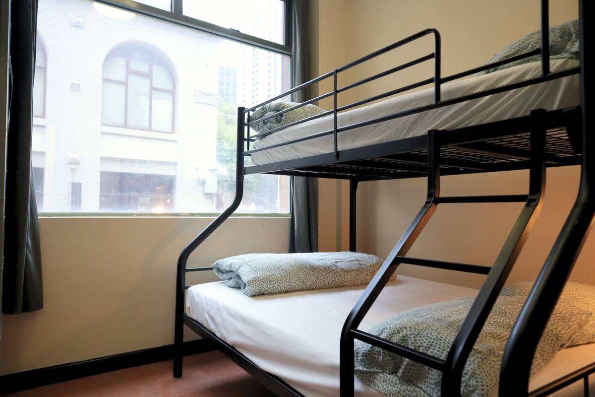 A bunk bed with a window view of a building.