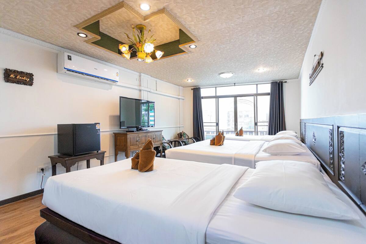 Una habitación de hotel con dos camas, televisión, escritorio y ventana con cortinas.