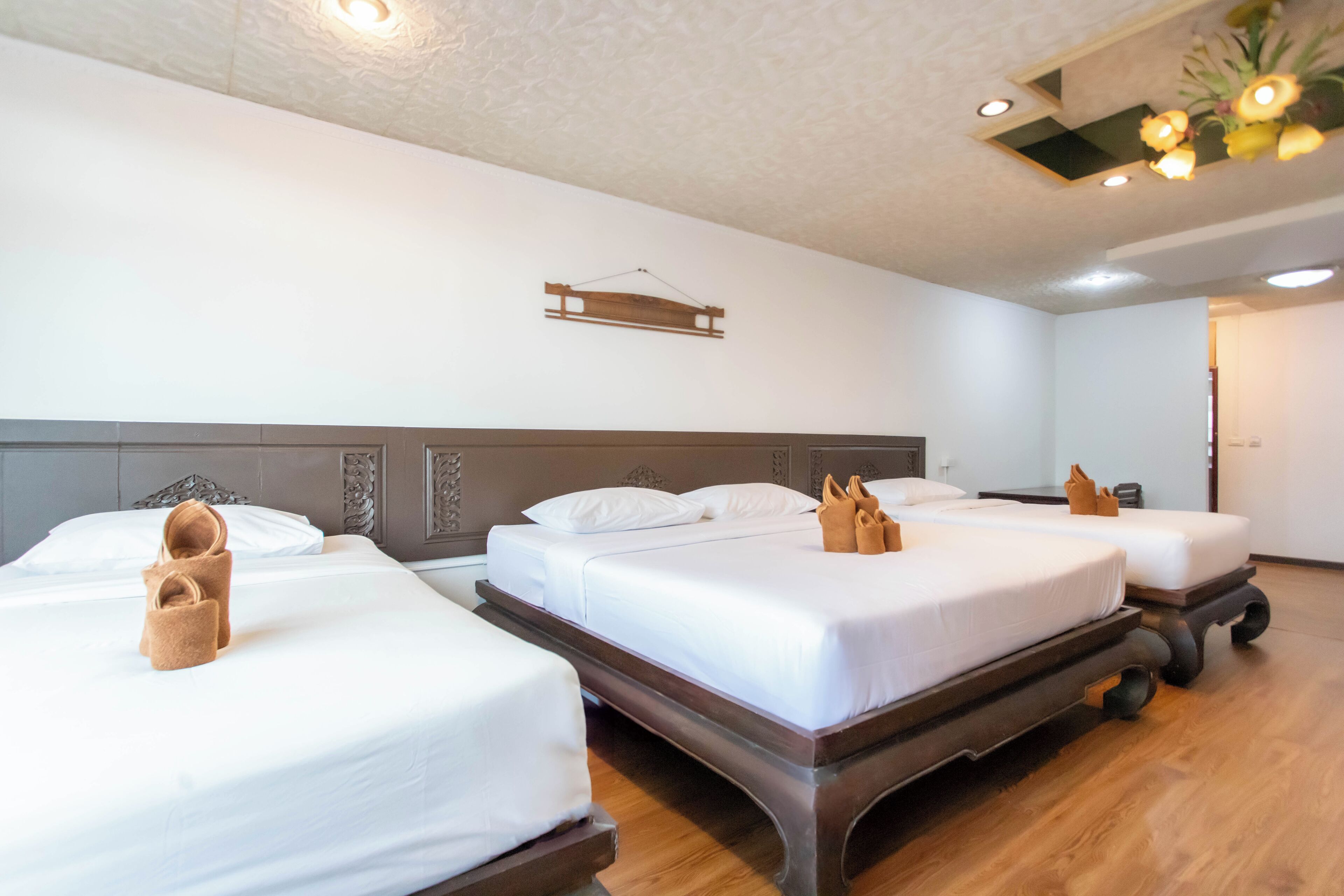 Une chambre d’hôtel avec trois lits, des têtes de lit en bois et un plancher en bois.