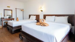 Een hotelkamer met twee bedden, een houten bureau, een spiegel en een airconditioning.