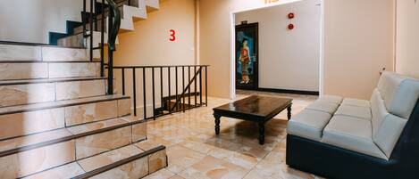 A lobby with a staircase, a sofa, and a coffee table.