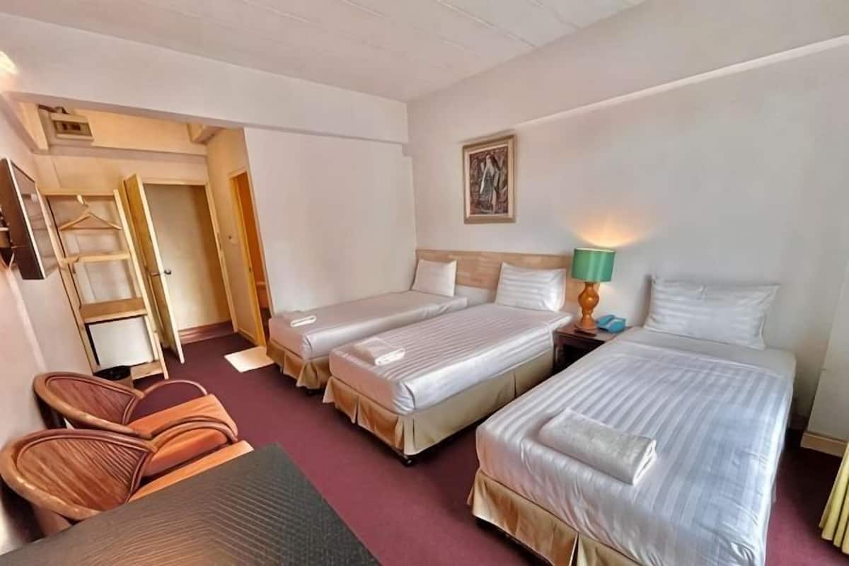 A hotel room with two beds, a chair, a desk, and a wardrobe.