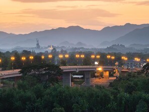 Un puente con farolas, rodeado de vegetación y montañas al fondo.