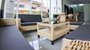 A modern living room with wicker furniture, large windows, and a view of the outside. - The Villa Chiangrai (Chiang Rai)