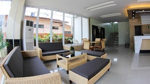 A modern hotel lobby with wicker furniture, a glass coffee table, and a reception desk. - The Villa Chiangrai (Chiang Rai)