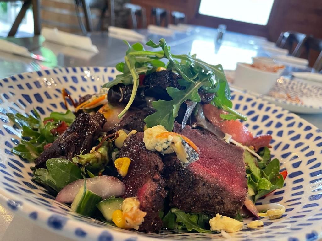 Une assiette de nourriture comprenant un steak et des légumes verts.