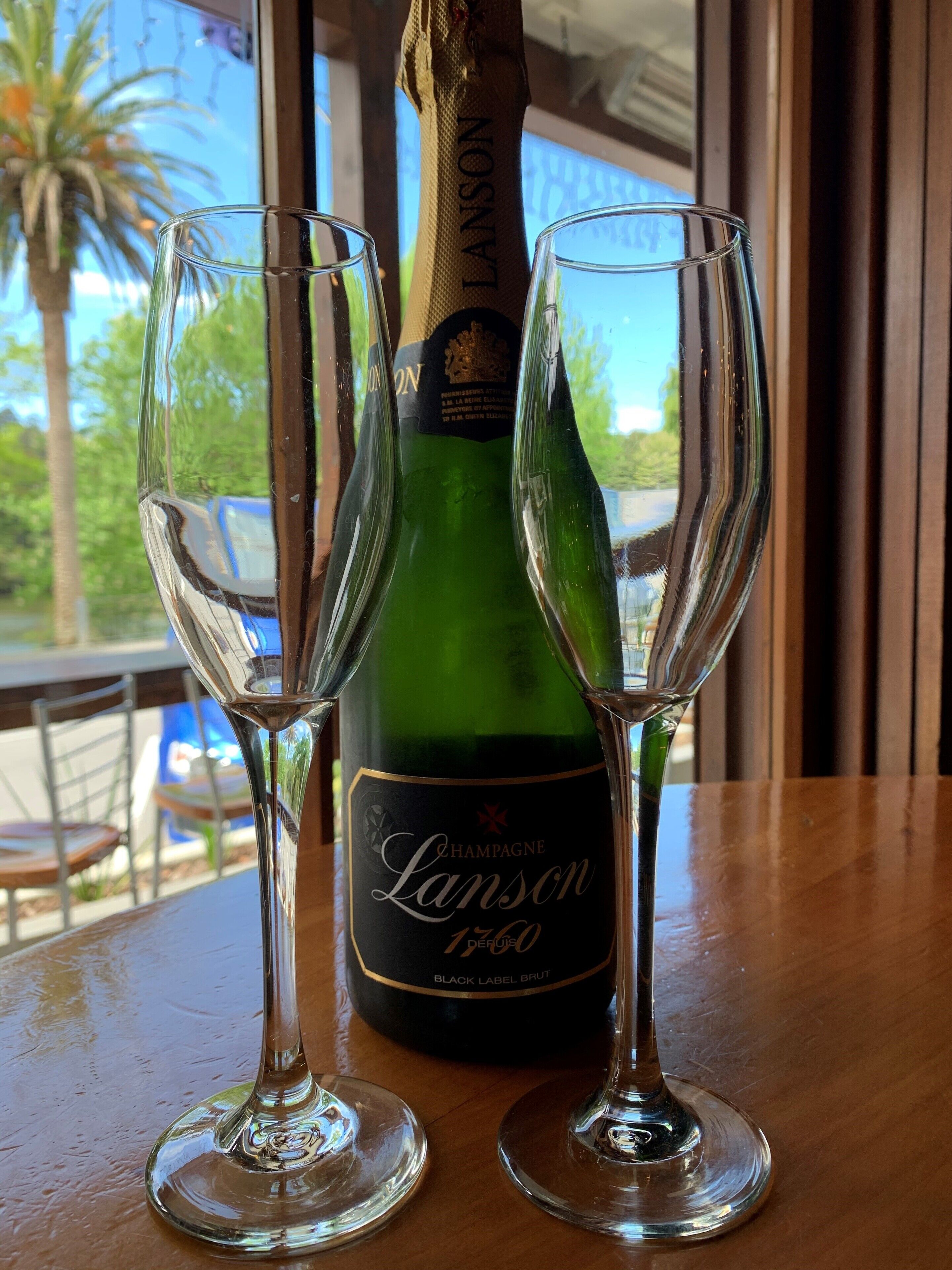 En flaske Lanson champagne og to glas på et bord.