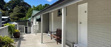 Un bâtiment doté d’un porche couvert, d’un banc et du numéro « 32 » peint sur le mur.