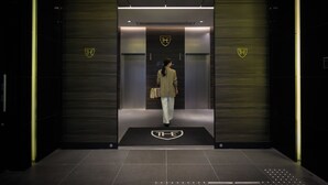 An elevator with a logo on the wall and a person walking towards it.