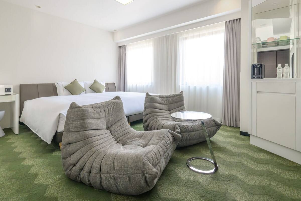 A hotel room with a bed, a desk, a chair, a round table, and a TV.