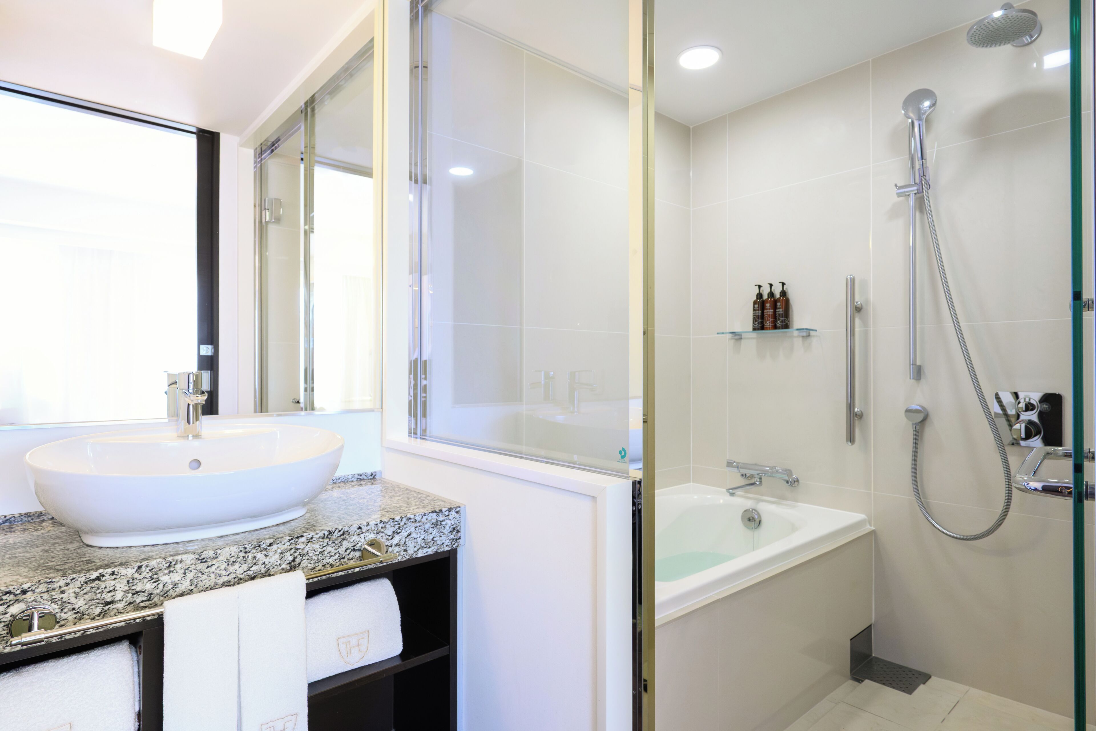 A modern bathroom with a large white sink, a glass-enclosed shower, and a bathtub.