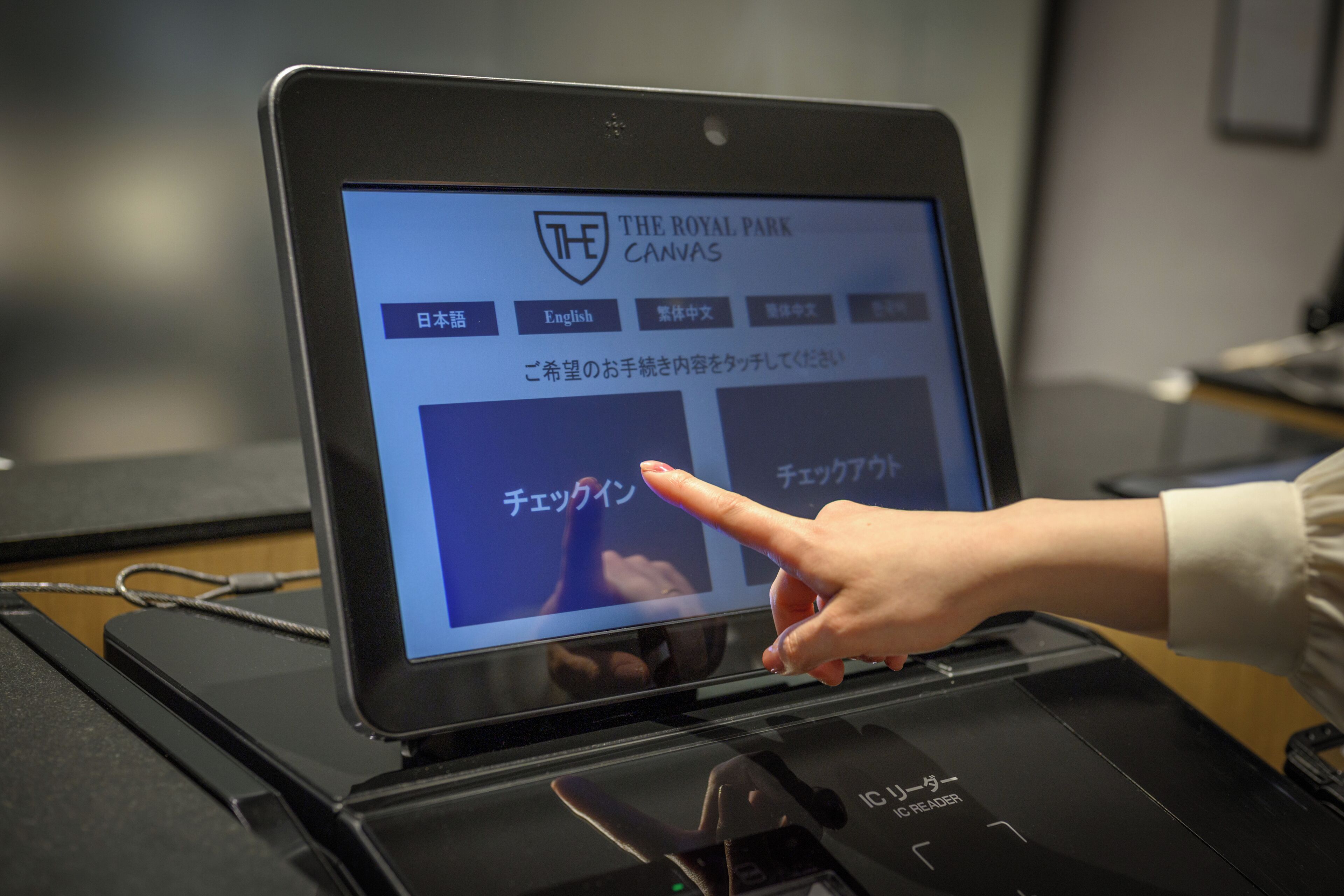 A laptop displaying a website with Japanese text and a logo labeled "THE ROYAL PARK CANVAS".