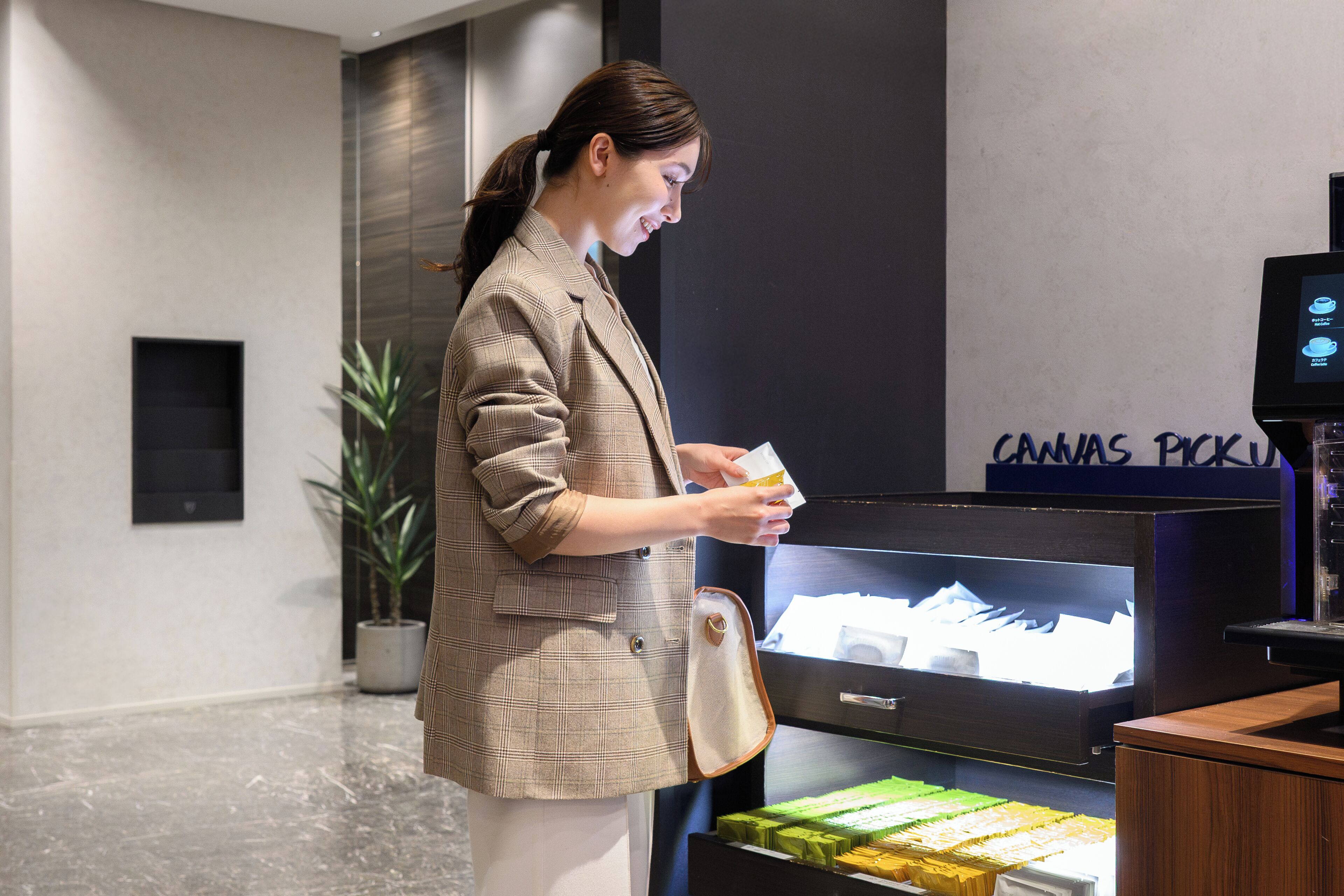 A woman in a checkered blazer standing in front of a display case with a sign reading 'CANVAS PICKING.'