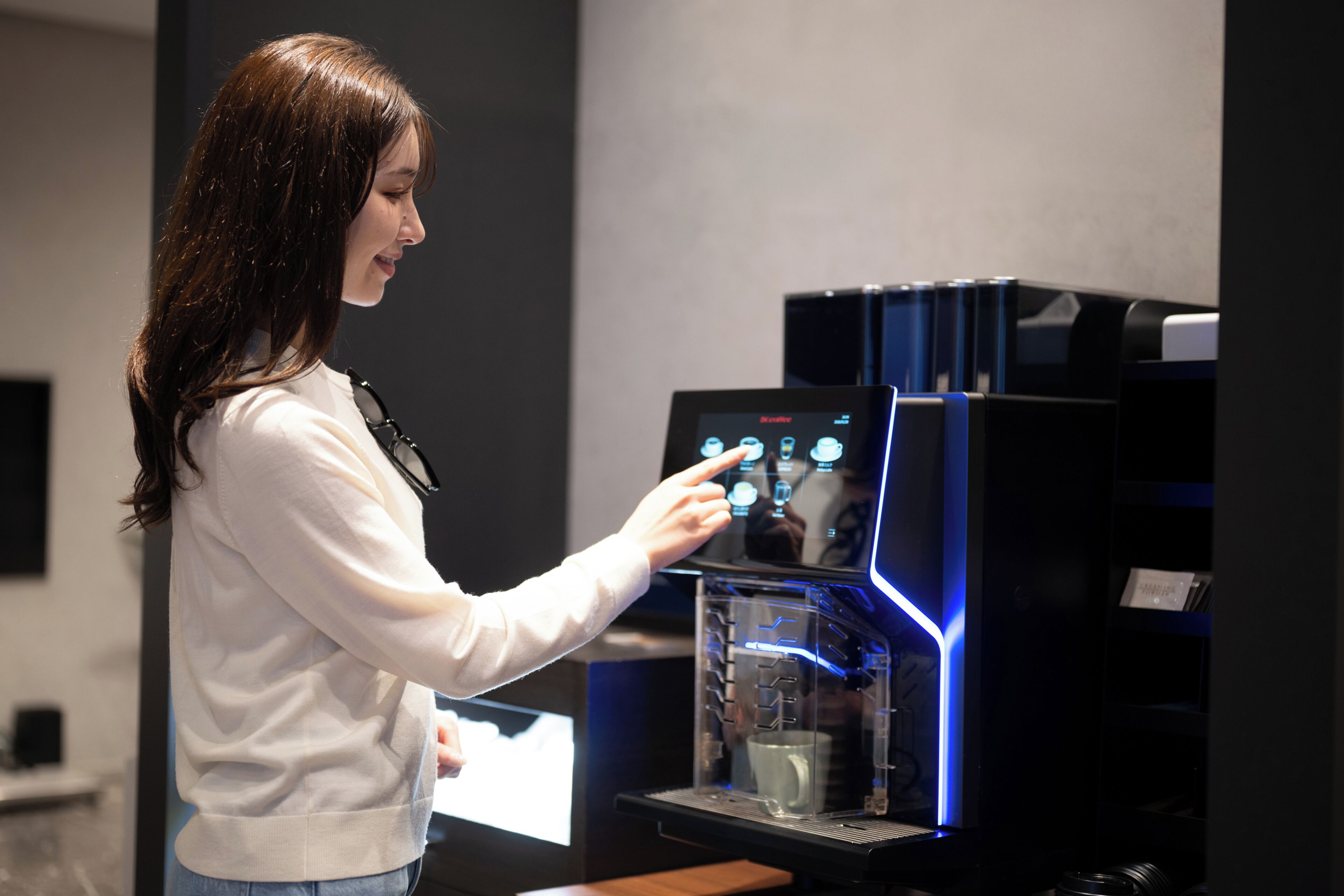 A person interacting with a coffee machine in a modern setting.
