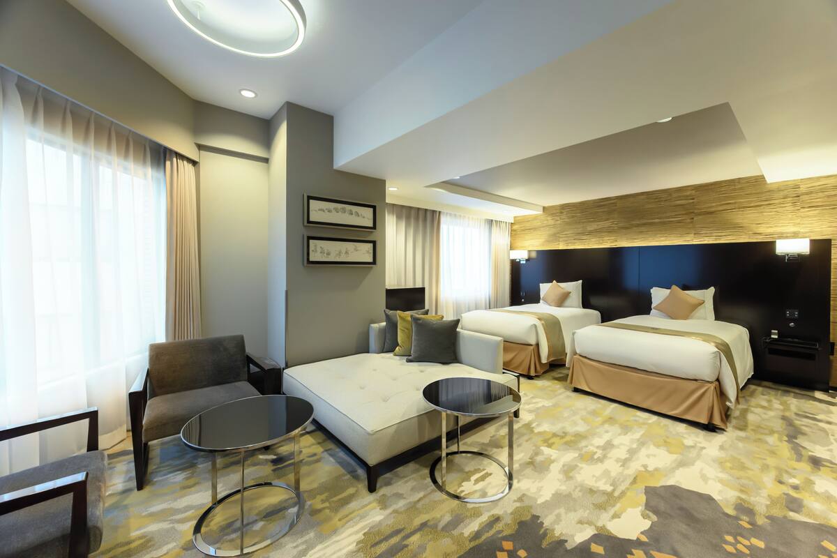 A modern hotel room with a large bed, a sofa, a small table, and a chair.