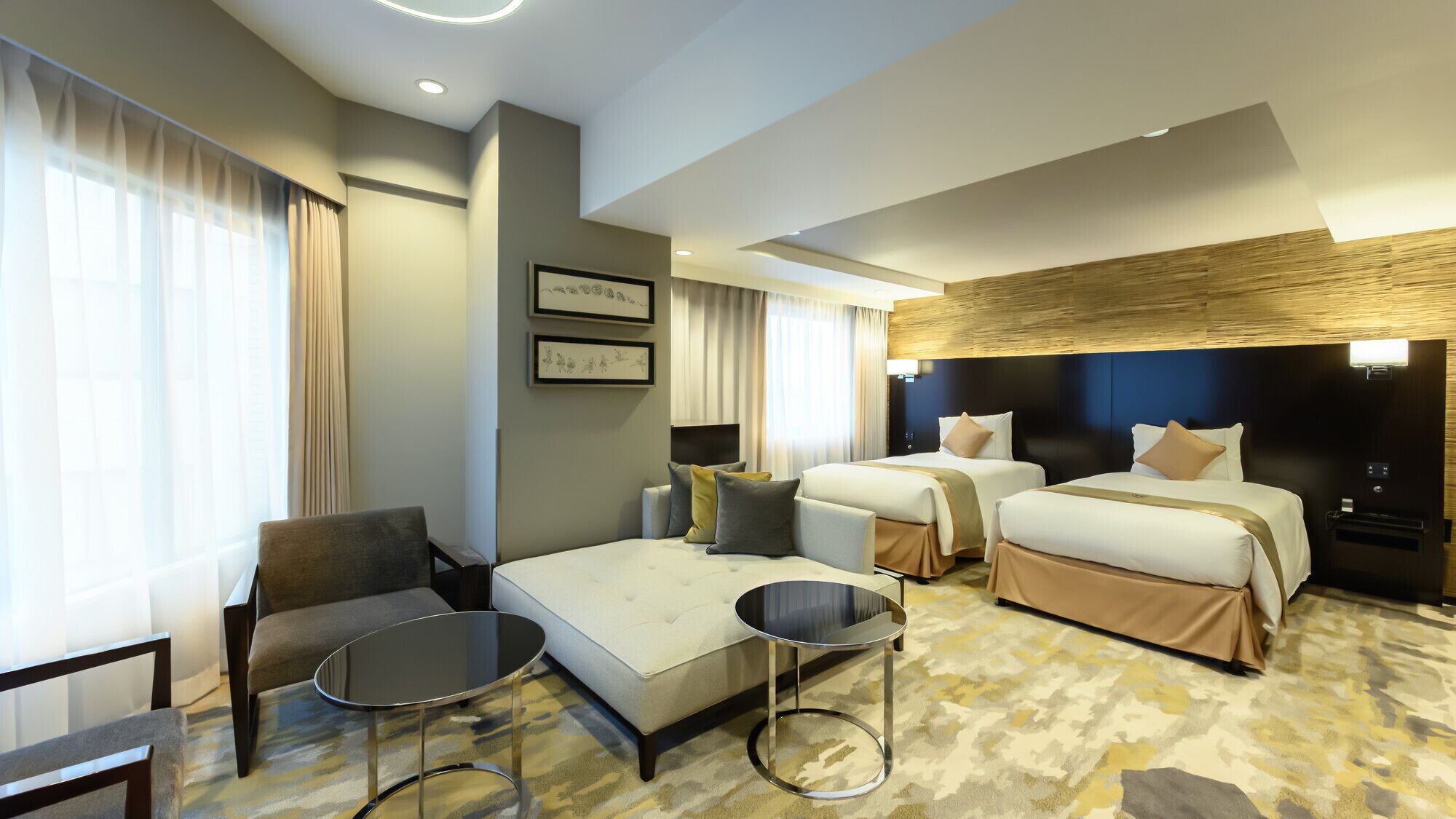 A hotel room with two beds, a sofa, a chair, and a small table.