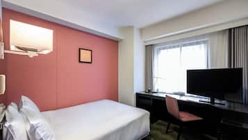 Habitación de hotel con cama, escritorio, silla, televisión y un cuadro en la pared.