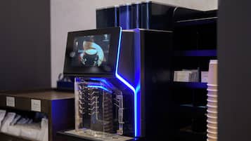 A coffee machine with a digital display, a clear water tank, and a blue-lit exterior.
