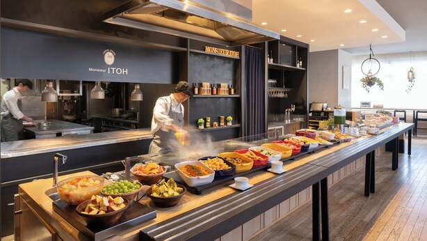 A buffet setup with various food items and a chef preparing food.