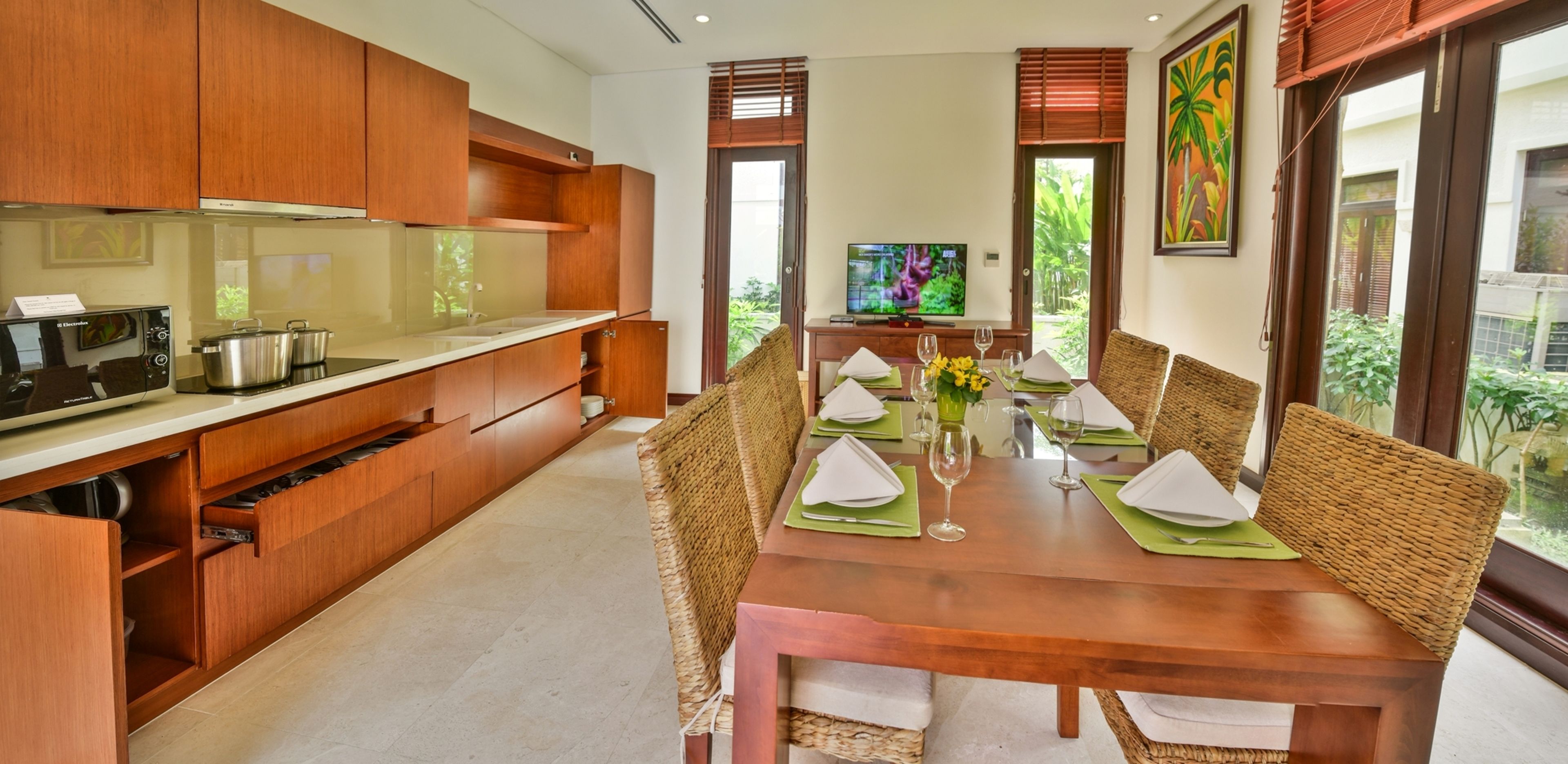 Una cocina moderna con armarios de madera y un comedor con una mesa de madera preparada para cuatro.