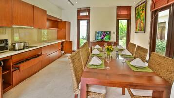 Una cocina moderna con armarios de madera y un comedor con una mesa de madera preparada para cuatro.