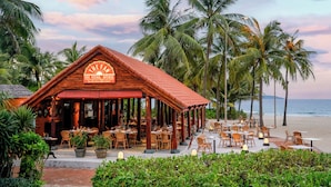 Een houten gebouw met een bord waarop staat 'The Steak House', gelegen aan een strand met palmbomen en uitzicht op de oceaan.