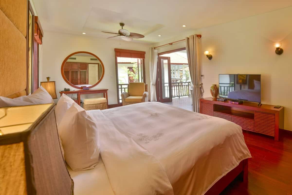A hotel room with a bed, a desk, a chair, a television, and a balcony door.