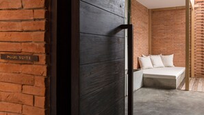 A hotel room with a brick wall, a bed with pillows, and a sign indicating a pool suite. - Sala Ayutthaya (Ayutthaya)