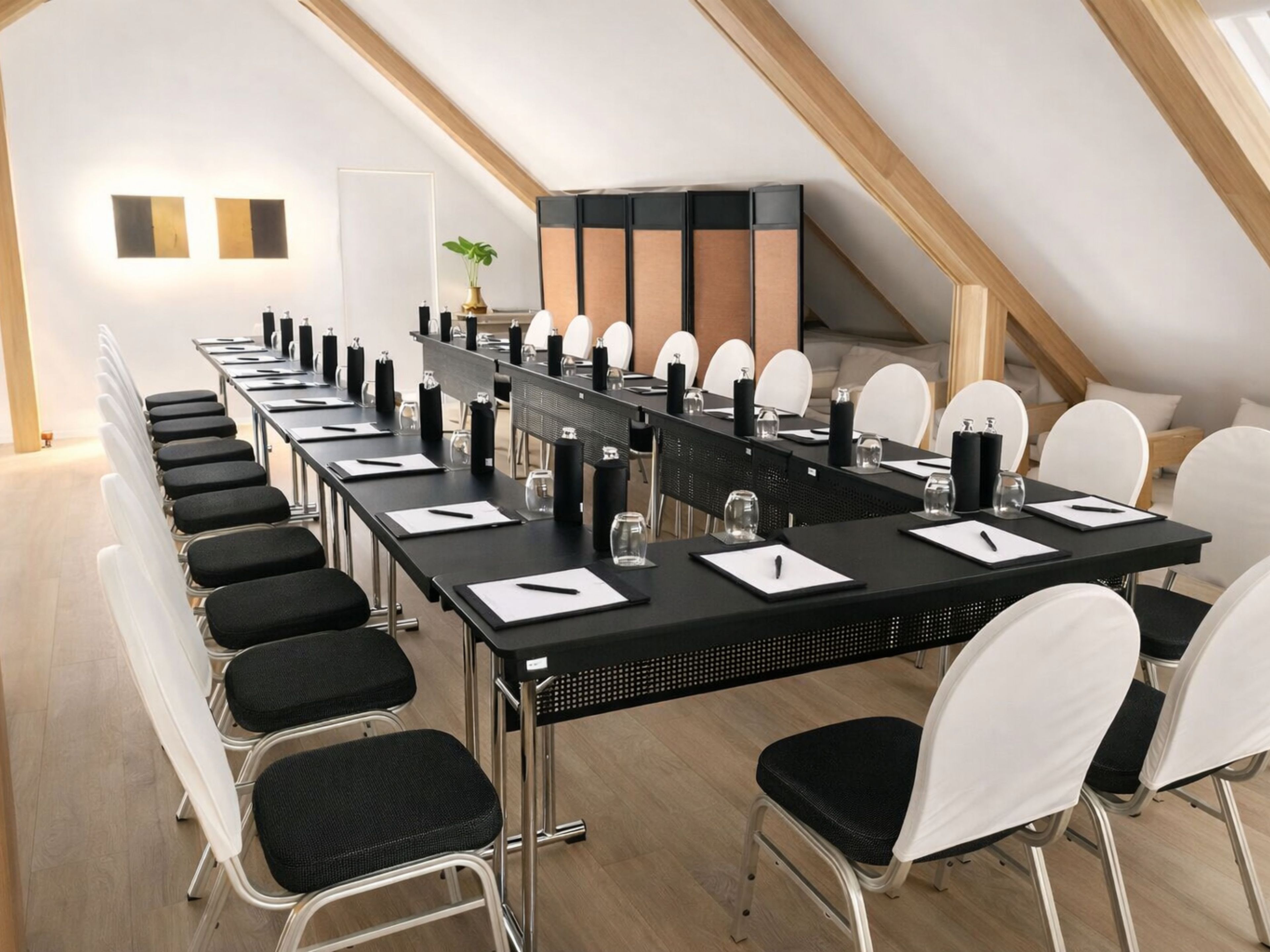 Uma sala de conferências com uma mesa comprida, cadeiras e uma planta.