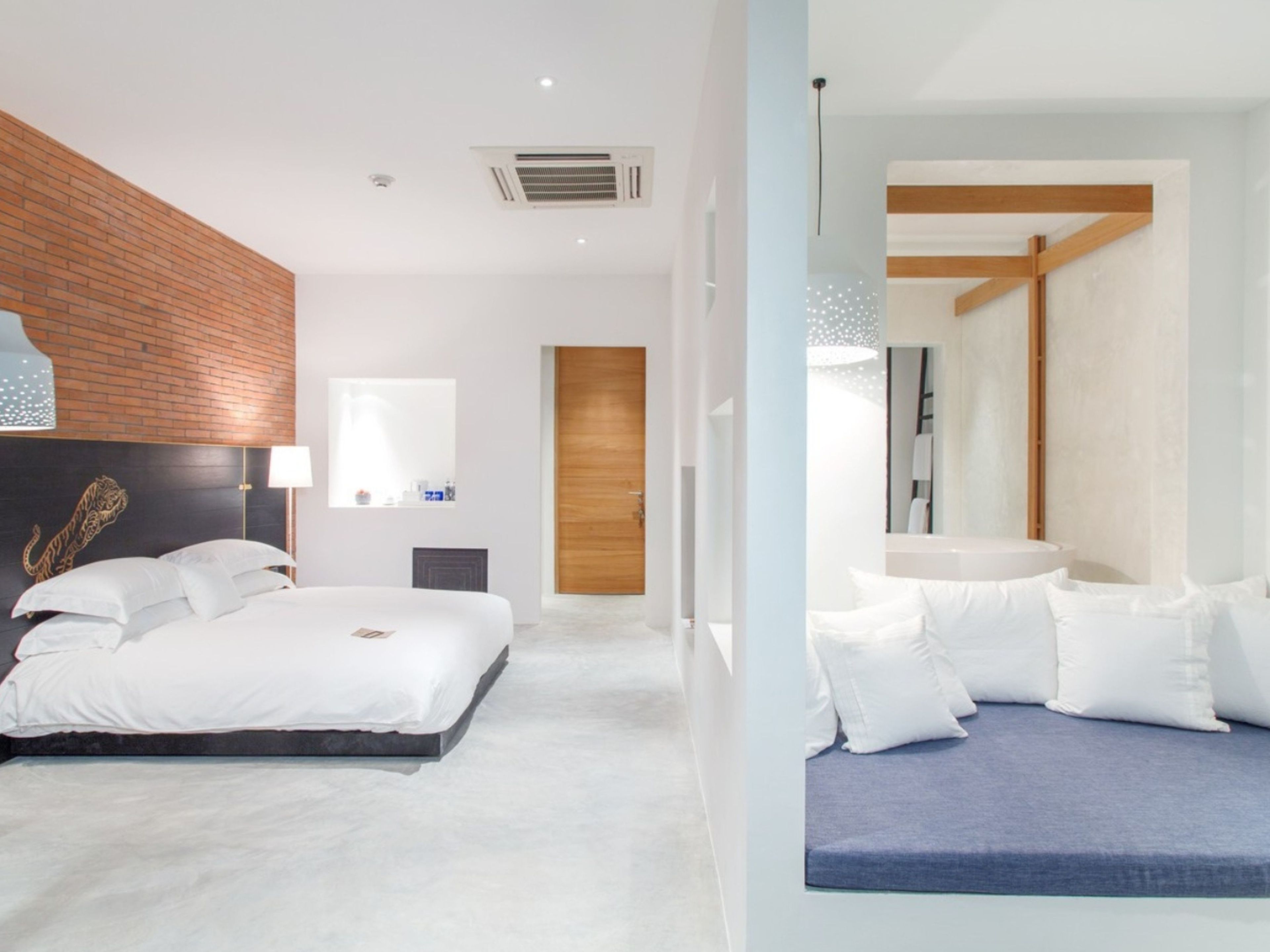 A modern bedroom with a large bed, a wooden headboard, a bedside table, and a nightstand.