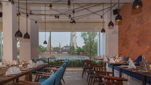 An indoor dining area with tables set for service, chairs, and hanging pendant lights. - Sala Ayutthaya (Ayutthaya)