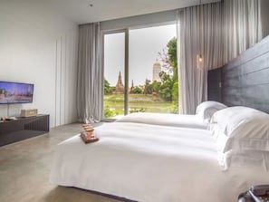Ein Hotelzimmer mit einem großen Bett, einem Fernseher und Blick auf einen Tempel durch das Fenster.