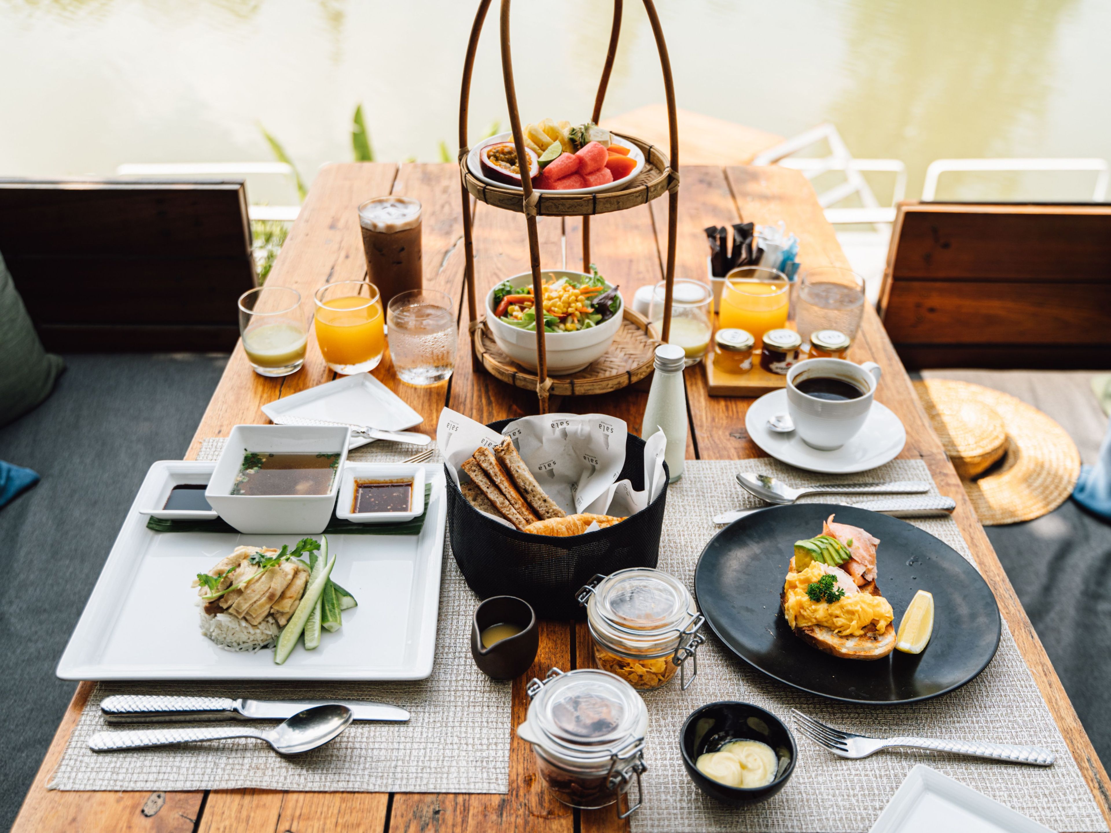 Mesa de madeira posta com diversos pratos, bebidas e acompanhamentos, indicando um momento de refeição.