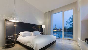 Habitación de hotel moderna con una cama grande, una mesita de noche, una lámpara y vistas a un templo por la ventana.