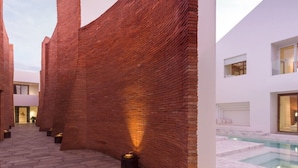 Un edificio moderno con fachada de ladrillo, zona de piscina y un camino de piedra.