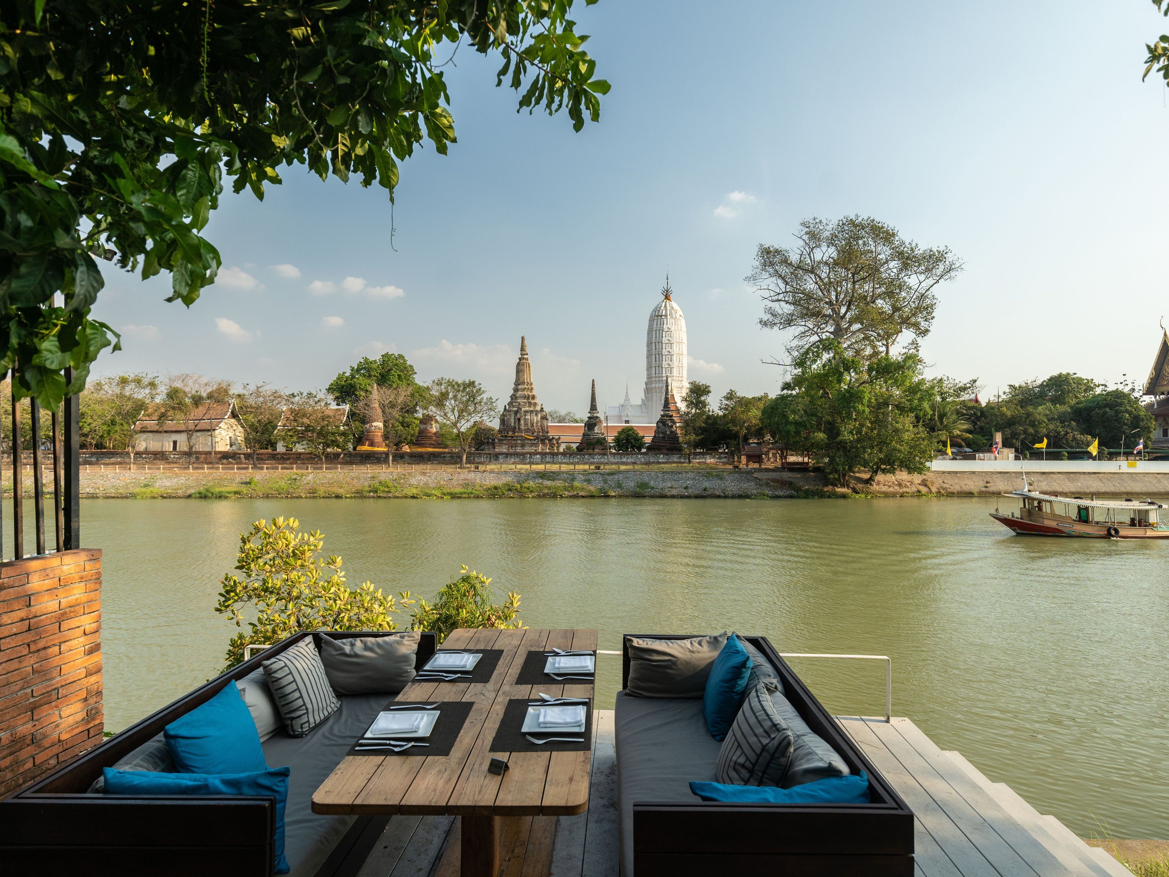 An outdoor seating area with a view of a temple and river.