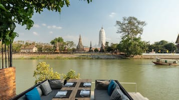 An outdoor seating area with a view of a temple and river.