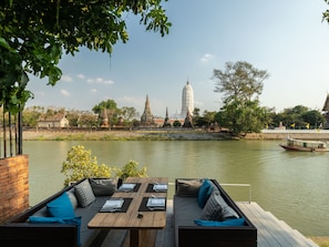 Un área de estar al aire libre con vista a un templo y un río.