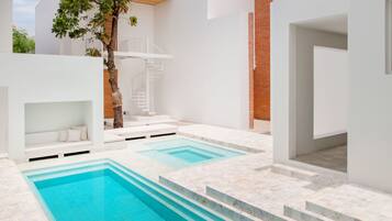 Zona de piscina exterior moderna con una escalera que lleva a una terraza en la azotea.