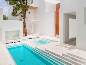 A modern outdoor swimming pool area with a staircase leading to a rooftop deck.