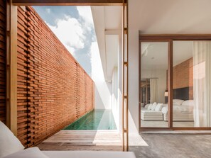 A modern hotel room with a brick exterior wall, a glass-enclosed pool, and a view of the sky. - Sala Ayutthaya (Ayutthaya)