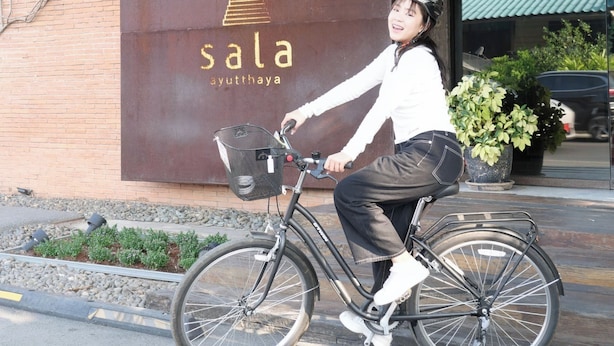 Una persona en bicicleta frente a un edificio con un letrero que dice 'sala ayuththaya'.