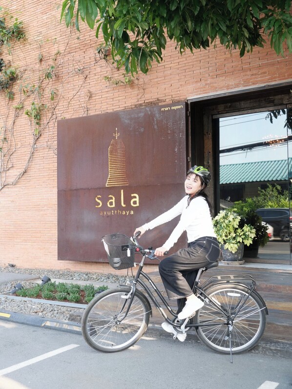 A person on a bicycle in front of a building with a sign that reads 'sala ayuththaya'. - Sala Ayutthaya (Ayutthaya)