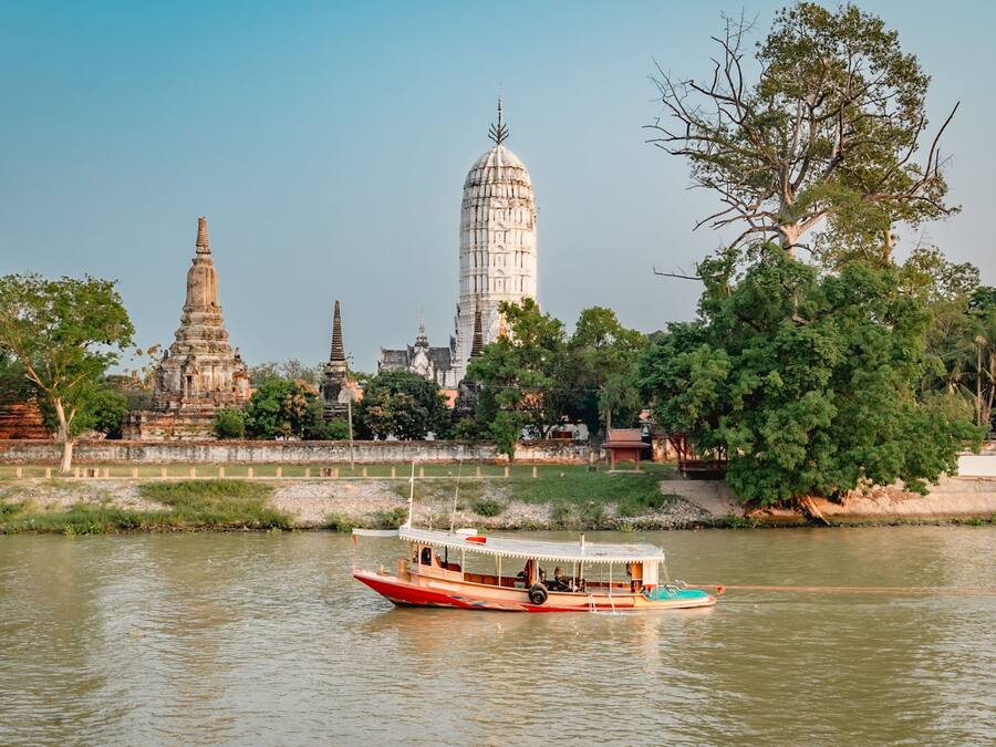A boat on a river with temple structures in the background.
