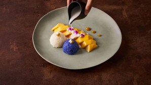 A hand pouring a liquid onto a plate with various food items. - Sala Ayutthaya (Ayutthaya)